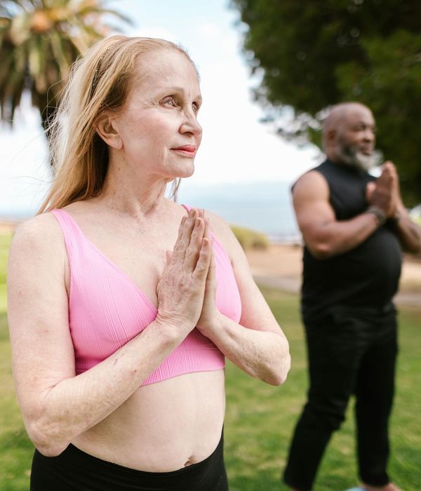 Woman in a calm yoga pose on a lilac background.